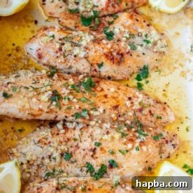 4 baked tilapia fillets in a pan.