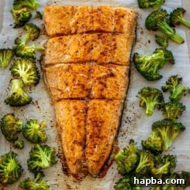 Large salmon fillet and roasted broccoli on a sheet pan