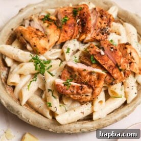 Creamy pasta in a bowl, topped with pan-seared chicken.