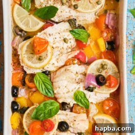 White fish fillets in a casserole dish baked with veggies.