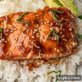 Teriyaki Salmon over rice with avocado slices in a bowl.