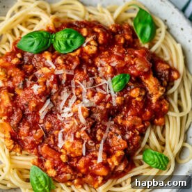 Spaghetti in a bowl topped with chicken Bolognese sauce.