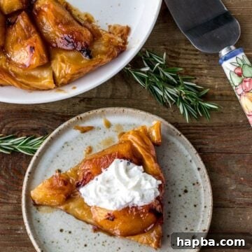 Slice of tarte tatin on a plate topped with cream, plate of large tarte tatin in the back