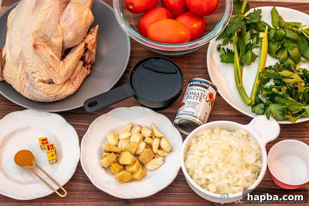Assortment of fresh ingredients for African chicken stew on a wooden chopping board, including tomatoes, onions, garlic, ginger, and herbs.