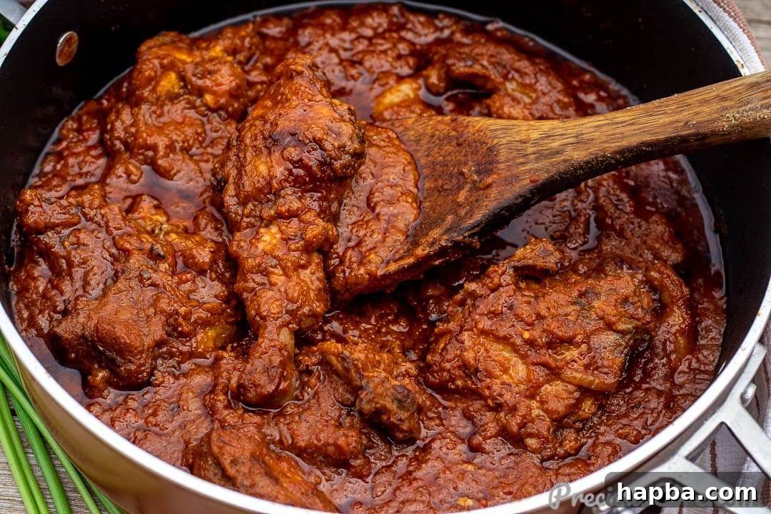 A pan filled with simmering African tomato chicken stew, ready to be served.