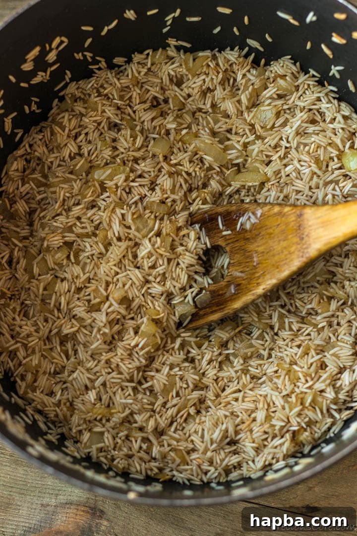 Raw rice, sautéed onion, and oil simmering together in a pot.